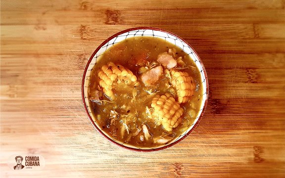 Plato de ajiaco criollo servido, viandas en trozos con pedazos de mazorca de maíz visibles