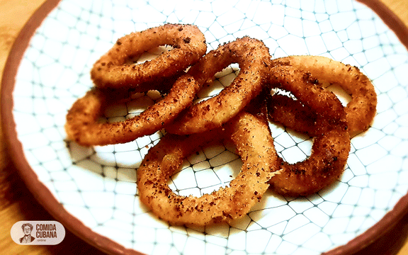 Plato de aros de cebolla empanizados servido, aros dorados y crujientes apilados