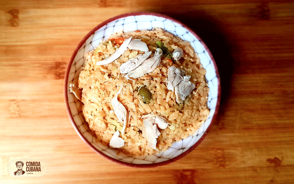 Plato de arroz con pollo servido, arroz con piezas de pollo visibles y grano suelto en el plato.