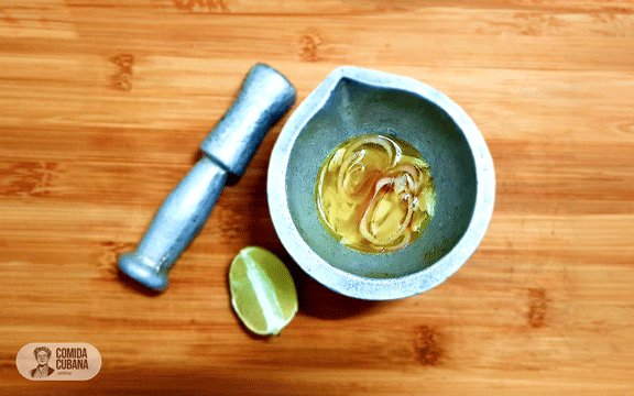 Mojo criollo en mortero, salsa líquida con cebollas visibles y aspecto brillante