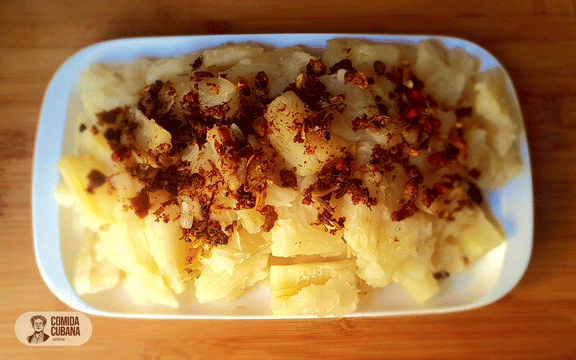 Plato de yuca con mojo servido, trozos de yuca con salsa por encima y aspecto brillante